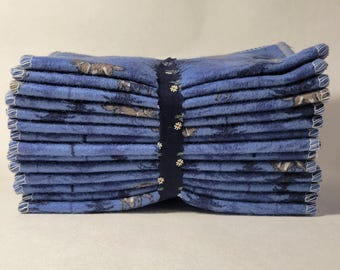 May include: A stack of blue flannel cloths with a white floral pattern and a dark blue ribbon tied around them.