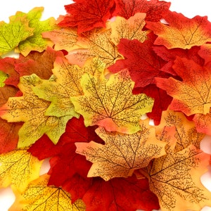 May include: A collection of artificial fall leaves in various shades of red, orange, and yellow. The leaves have a realistic vein pattern and are perfect for crafting or decorating.