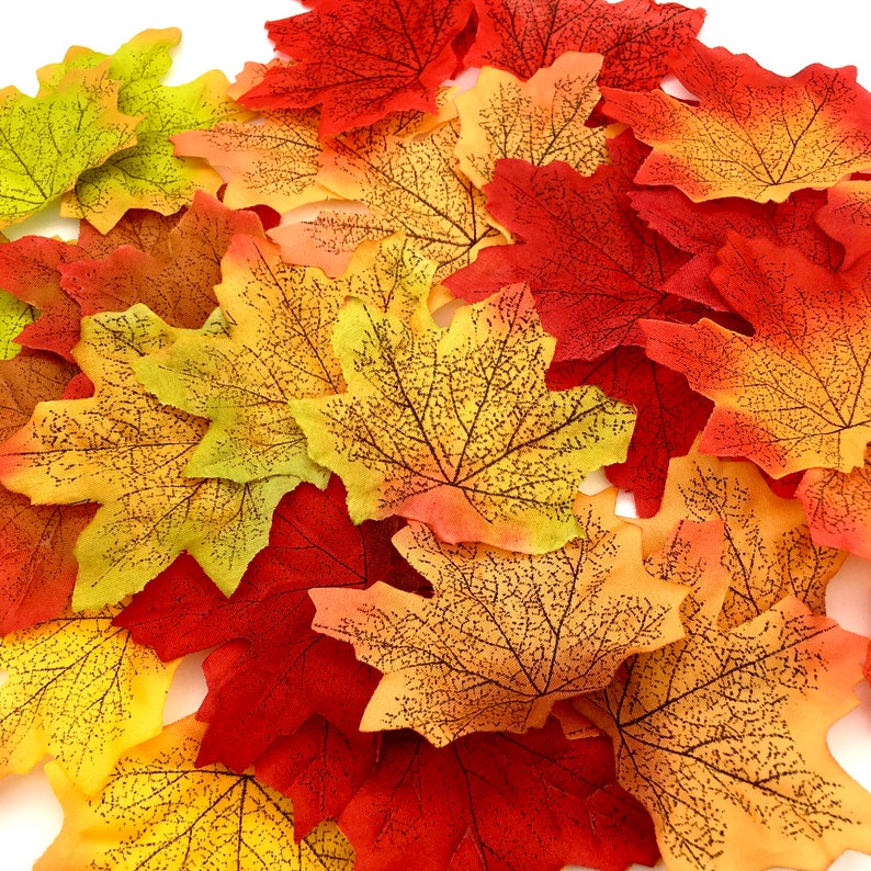 May include: A collection of artificial fall leaves in various shades of red, orange, and yellow. The leaves have a realistic vein pattern and are perfect for crafting or decorating.