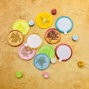 May include: Assortment of colorful wax seals with various designs, including a bee, a flower, and the words "Thank You" and "Wedding".