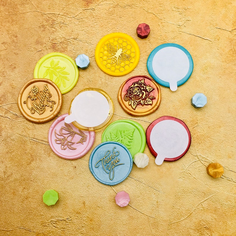 May include: Assortment of colorful wax seals with various designs, including a bee, a flower, and the words "Thank You" and "Wedding".