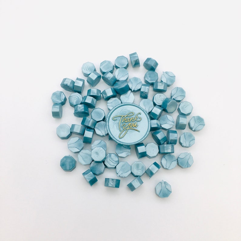 May include: A pile of blue wax seals with a single wax seal with the words "Thank You" in gold lettering.