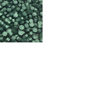 May include: A close-up image of a large quantity of dark green wax seal beads. The beads are hexagonal in shape and have a slightly textured surface.