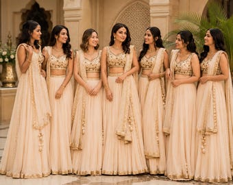 Könnte beinhalten: Eine Gruppe von sieben passenden beigen Lehengas mit ärmellosen bauchfreien Oberteilen mit aufwendiger Goldstickerei, hoch taillierten Faltenröcken und passenden transparenten Dupattas, die über die Schultern drapiert sind und goldene Bordüren aufweisen.