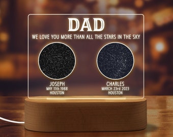 May include: A white LED light with a wooden base displays a personalized message "DAD WE LOVE YOU MORE THAN ALL THE STARS IN THE SKY" with two star constellations representing birth dates and locations. The text includes the names "Joseph" and "Charles" with their birth dates and locations.