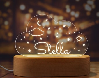 May include: A white acrylic cloud-shaped night light with a wooden base. The cloud has a crescent moon, stars, and the name "Stella" written on it.