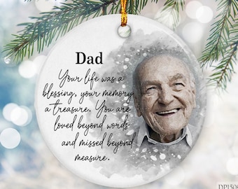 May include: A white ceramic Christmas ornament with a watercolor-style image of a smiling man. The ornament has the text "Dad Your life was a blessing, your memory a treasure. You are loved beyond words and missed beyond measure."