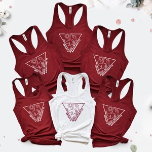 May include: Six tank tops with a white triangle design featuring a desert landscape and the text "Bride's Bachelorette". The tank tops are maroon and white.