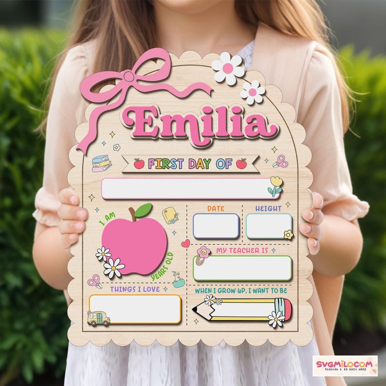 Peut inclure: Une plaque en bois festonn&eacute;e pour le premier jour d'&eacute;cole avec le pr&eacute;nom Emilia en lettres roses. Le panneau comprend des sections pour la date, la taille, l'enseignant et les centres d'int&eacute;r&ecirc;t, d&eacute;cor&eacute;es d'illustrations de pommes et de fleurs.