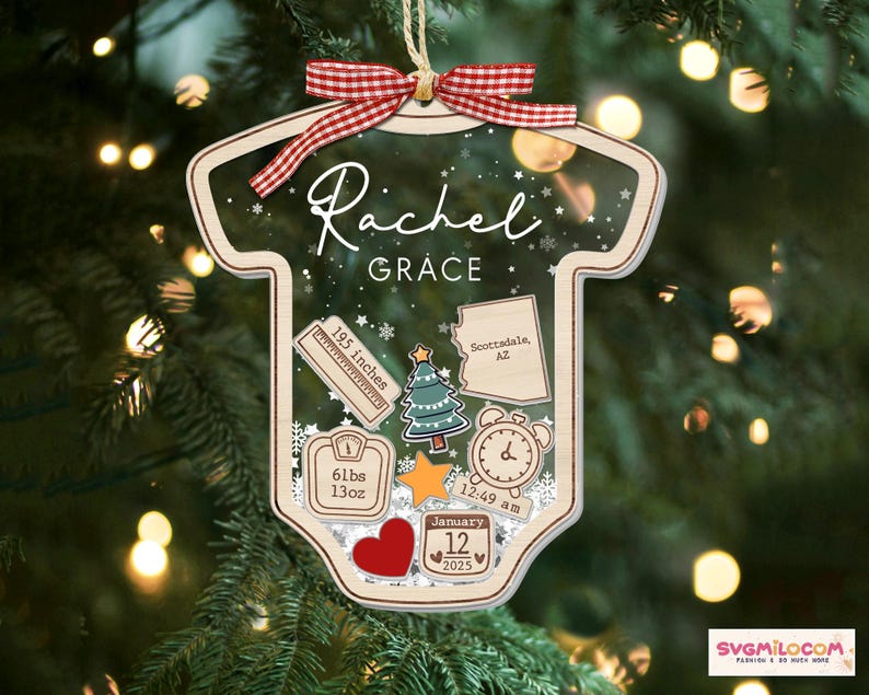 May include: A clear acrylic ornament shaped like a baby bodysuit, featuring a red and white gingham ribbon. It displays the name Rachel Grace, a ruler marked 195 inches, a map of Arizona, a Christmas tree, a scale reading 61lbs 13oz, a clock, and a calendar.
