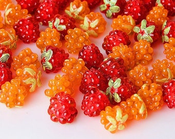Può includere: Una collezione di perline di vetro arancioni e rosse a forma di lamponi. Le perline sono perfette per la creazione di gioielli o per l'artigianato.