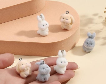 May include: Five plush bunny charms in various colors, including white, gray, and beige. Each charm has a silver loop for attaching to a keychain or bag.