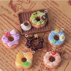 May include: Six colorful donut charms with different toppings, including sprinkles, chocolate, and fruit. Each charm has a metal loop for hanging.