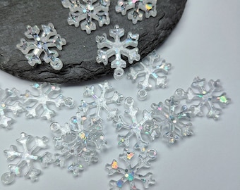 May include: A collection of 12 clear iridescent snowflake charms with glitter accents. The charms have a hole at the top for hanging.