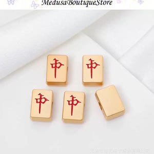 Puede incluir: Fichas de Mahjong doradas con caracteres chinos rojos. Las fichas rectangulares tienen bordes redondeados. La imagen incluye el texto "Medusa Boutique Store".