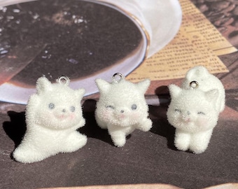 Può includere: Tre ciondoli a forma di gatto in peluche bianco e soffice con anelli di salto argentati. I ciondoli sono in varie pose, tra cui seduti, in piedi e sdraiati. I ciondoli hanno occhi neri e guance rosa.