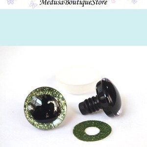 May include: A pair of black plastic safety eyes with green glitter accents, a washer, and a plastic insert. The eyes are 12mm in diameter.