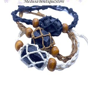 May include: Three black tourmaline crystal bracelets with brown wooden beads and macrame string. The bracelets are in a variety of colors, including black, brown, and white.