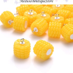 May include: A group of yellow corn on the cob charms with silver jump rings. The charms are ideal for adding a touch of whimsy to jewellery or crafts.