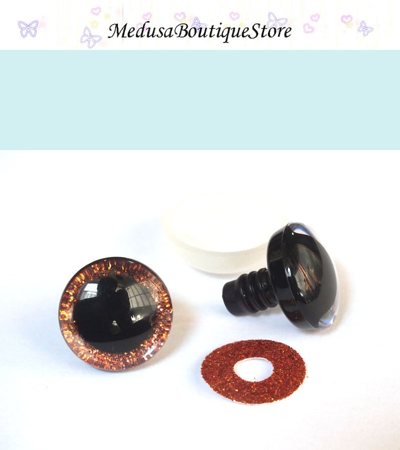 May include: A pair of brown and black safety eyes with a glitter rim, a black plastic washer, and a white plastic washer. The safety eyes are used for making stuffed animals.