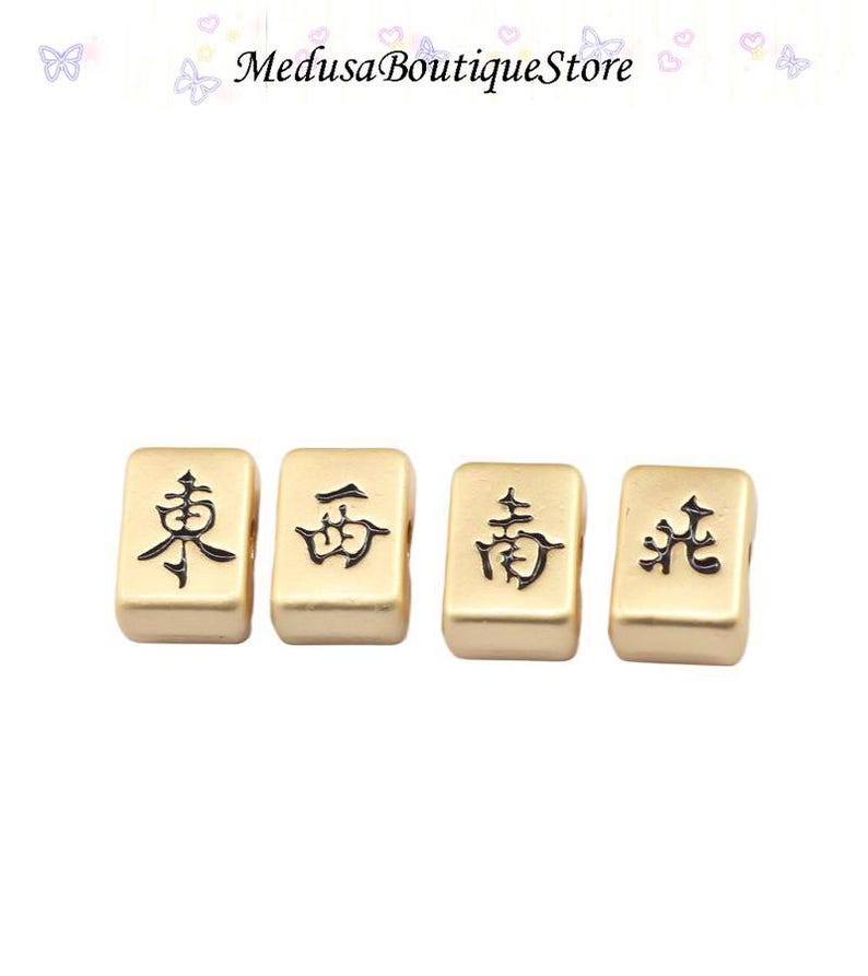 Puede incluir: Cuatro fichas de Mahjong doradas con caracteres chinos negros. Las fichas son rectangulares y tienen bordes redondeados. El texto "Medusa Boutique Store" est&aacute; en la parte superior de la imagen.