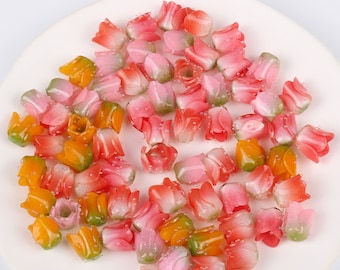 Peut inclure: Un ensemble de perles de fleurs en plastique colorées dans des tons de rose, orange et vert. Les perles sont en forme de tulipes et ont une finition brillante.