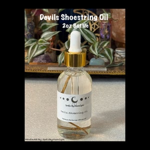 May include: A clear glass bottle labeled "Devils Shoestring Oil" with a gold cap and dropper. The bottle contains a clear liquid and a piece of shoestring. The label reads "Spells By Moonlight" and "2oz Bottle".