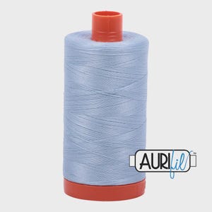 May include: A spool of light blue thread with a red top and base. The thread is tightly wound around the spool. The brand name "AURIfil" is printed on the side of the spool.