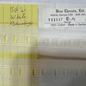 May include: White cotton blading, 5/8" wide, with a repeating geometric pattern. The image includes a yellow tag with handwritten details and a label from Bear Threads, Ltd. Made in Switzerland.