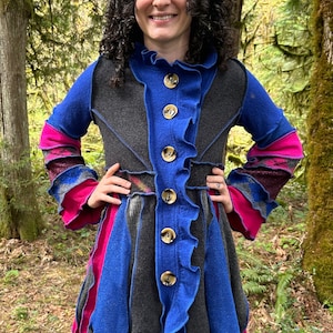 May include: A long-sleeved, multi-colored jacket with a ruffled hem and a button-up front. The jacket is made of a soft, knitted fabric and features a variety of colors, including blue, pink, and gray.