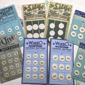 May include: Assortment of vintage button cards with various designs and colors. The cards feature different brands, including 'Briton', 'Clive', 'WinsO', 'Silys', and 'The Diamond Card'. Each card displays a grid of white buttons with two holes.