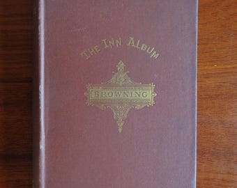 May include: A maroon-colored book titled "The Inn Album" by Browning. The title and author's name are in gold lettering. The book has a decorative gold emblem in the center.
