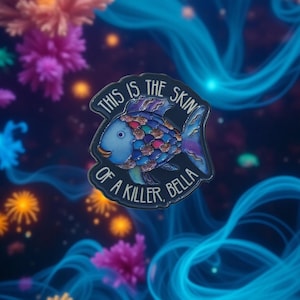 Könnte beinhalten: Ein farbenfroher Emaille-Pin mit einem stilisierten Fisch und dem Text "THIS IS THE SKIN OF A KILLER, BELLA." Der Fisch hat einen blauen Körper mit einem Regenbogen aus Schuppen. Der Pin befindet sich vor einem dunklen Hintergrund mit blauen Wirbeln und bunten floralen Akzenten.