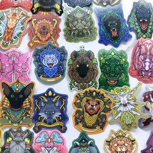 May include: A collection of colourful stickers featuring various animal heads and creatures set within ornate crests and shields. The designs include a giraffe, lion, boar, gorilla, dinosaur, butterfly, tiger, hyena, crocodile, cat, wolf, bear, and bird.