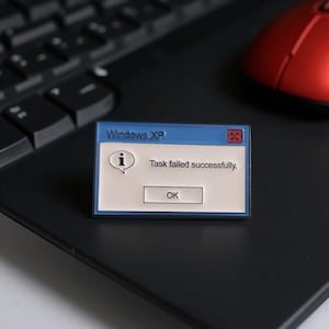 Pode incluir: Um alfinete de esmalte azul e branco em forma de mensagem de erro do Windows XP. O alfinete diz "Windows XP" na parte superior, com o texto "Task failed successfully." e um botão "OK". Um rato de computador vermelho e um teclado de laptop preto estão no fundo.