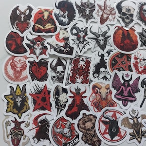 Könnte beinhalten: Eine Sammlung von Aufklebern mit okkulten und gotischen Designs. Die Aufkleber zeigen gehörnte Figuren, Totenköpfe, Pentagramme und andere dunkle Symbole in Rot, Schwarz und Weiß. Die Aufkleber sind in verschiedenen Formen und Größen.