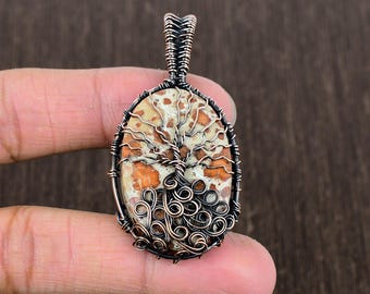 May include: A copper wire wrapped pendant featuring a tree of life design with a brown and white agate stone.