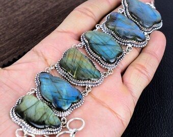 May include: A silver bracelet with five large, iridescent labradorite stones. The stones are set in silver and have a blue-green color with flashes of gold.