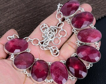 May include: A silver necklace with a chain and eight oval-shaped, faceted, dark red gemstones.
