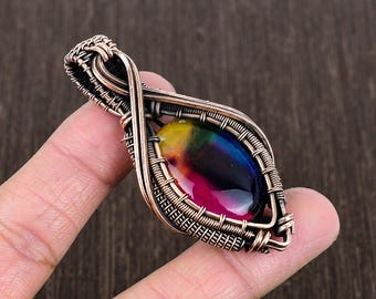 Peut inclure: Un pendentif en forme de larme avec une pierre précieuse irisée arc-en-ciel et un enroulement de fil de cuivre. Le pendentif est en forme de larme et possède une bélière en cuivre pour l'attacher à une chaîne.
