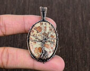 May include: A copper wire wrapped pendant featuring a tree of life design with a brown and white dendritic agate stone.