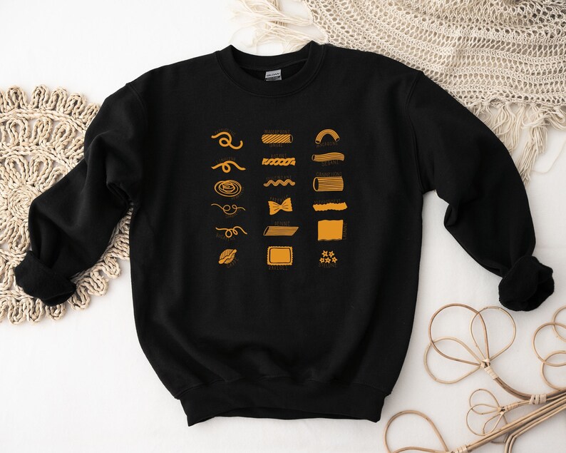 Peut inclure: Sweat-shirt noir avec un graphique de diff&eacute;rents types de p&acirc;tes avec leurs noms en texte orange.