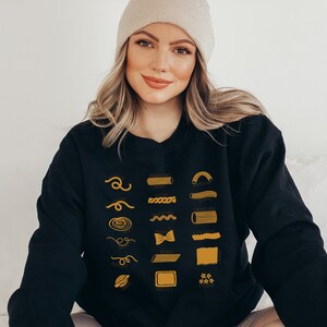 Peut inclure: Un sweat-shirt noir avec un graphique de diff&eacute;rents types de p&acirc;tes, chacun &eacute;tiquet&eacute; avec son nom en texte jaune. Les noms incluent : Spaghetti, Rigatoni, Rotini, Penne, Farfalle, Orecchiette, et plus.