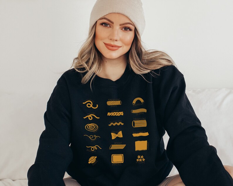Peut inclure: Un sweat-shirt noir avec un graphique de diff&eacute;rents types de p&acirc;tes, chacun &eacute;tiquet&eacute; avec son nom en texte jaune. Les noms incluent : Spaghetti, Rigatoni, Rotini, Penne, Farfalle, Orecchiette, et plus.