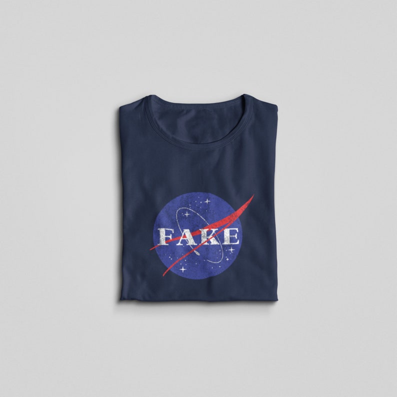 K&ouml;nnte beinhalten: Ein marineblaues T-Shirt mit einem Vintage-NASA-Logo mit dem Wort "FAKE" in wei&szlig;er Schrift.