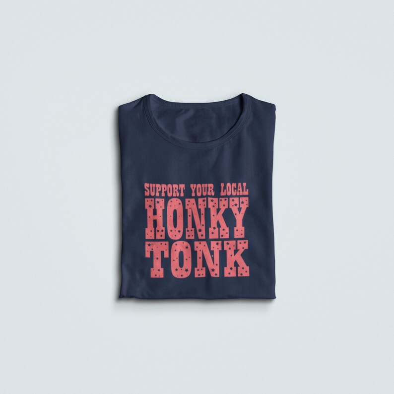 May include: A navy blue t-shirt with the text "SUPPORT YOUR LOCAL HONKY TONK" printed in pink with a polka dot pattern.