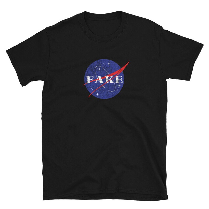 K&ouml;nnte beinhalten: Schwarzes T-Shirt mit einem blau-roten NASA-inspirierten Logo, auf dem "FAKE" in wei&szlig;er Schrift steht.