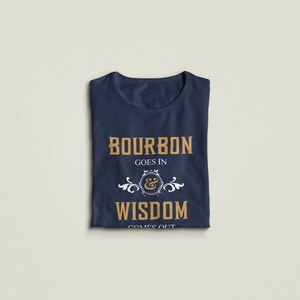 May include: A navy blue t-shirt with the text "Bourbon goes in & wisdom comes out" in gold lettering. The text is surrounded by a white decorative design.