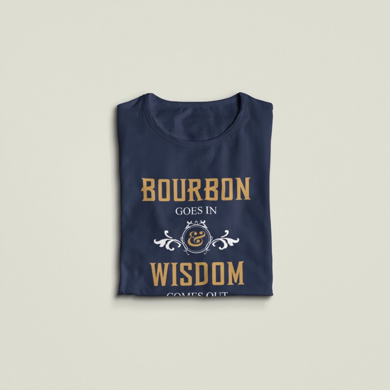 May include: A navy blue t-shirt with the text "Bourbon goes in & wisdom comes out" in gold lettering. The text is surrounded by a white decorative design.