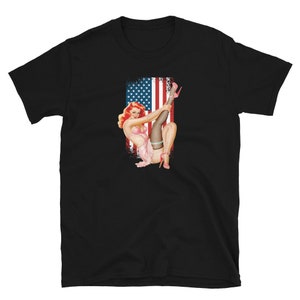 May include: A black t-shirt with a vintage pin-up style illustration of a woman in a pink dress and red heels, posed against a red, white, and blue American flag.